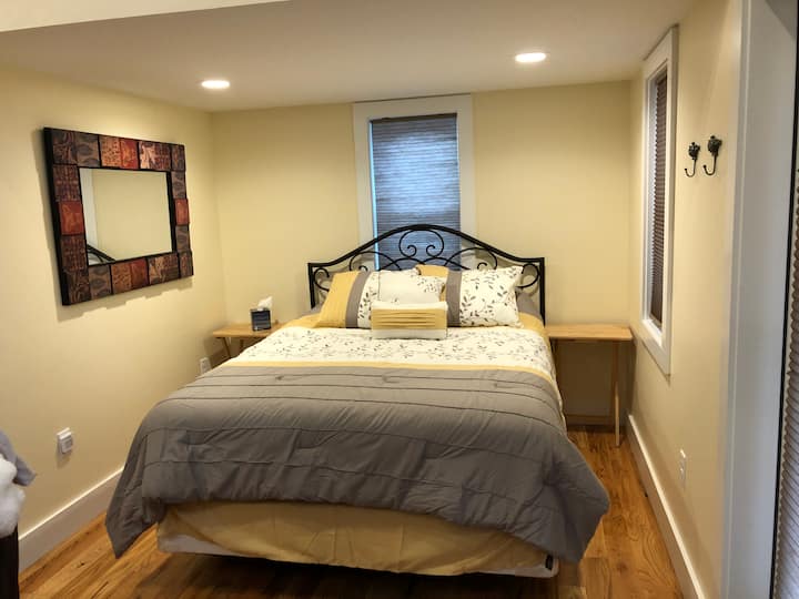 クイーンサイズベッドを備えた寝室。両方の窓からのツリートップの眺め。 