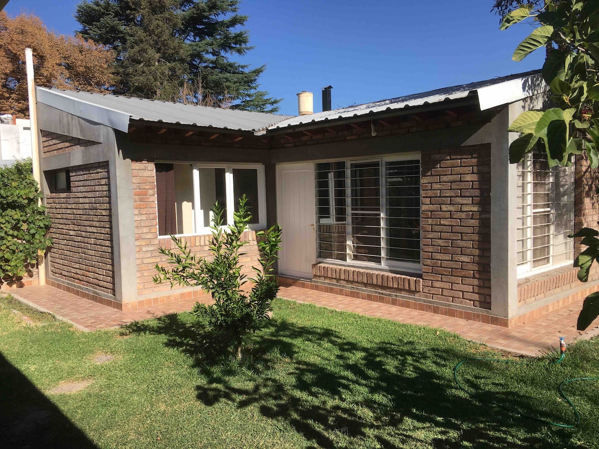 The exterior of the apartment showcases a brick facade and large windows that allow natural light to fill the interior. A well-maintained garden area features grass and small shrubs, providing a pleasant outdoor space. A covered porch adds to the charm of the entrance.