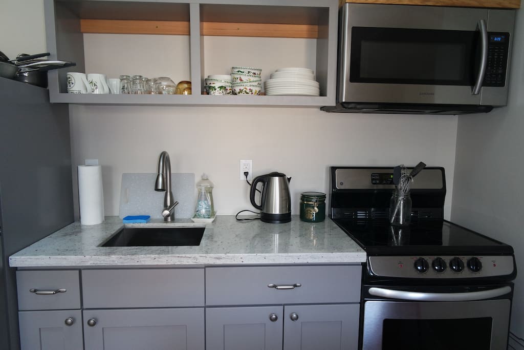 Close up of the studio kitchen complete with stove, oven, microwave, small refrigerator, toaster, coffee maker, and hot water boiler.