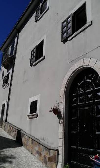La facciata della casa con il grande portone in legno intagliato.