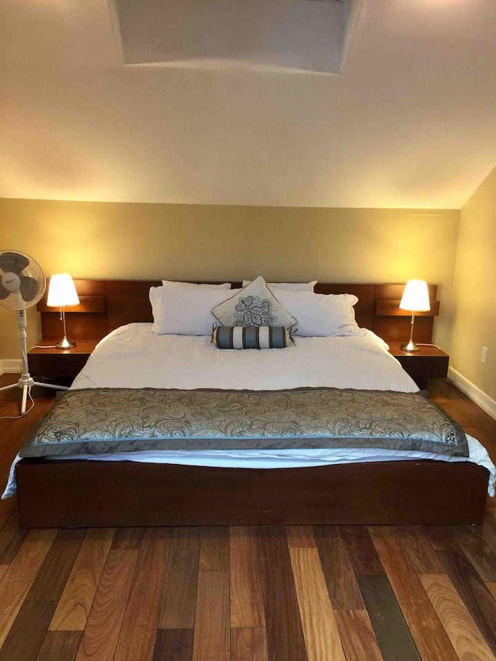 King size master bed with 2 bed stands, closet to the right.