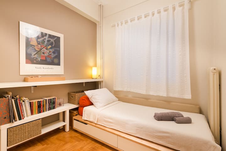 Un dormitorio más pequeño con una cama de una plaza...