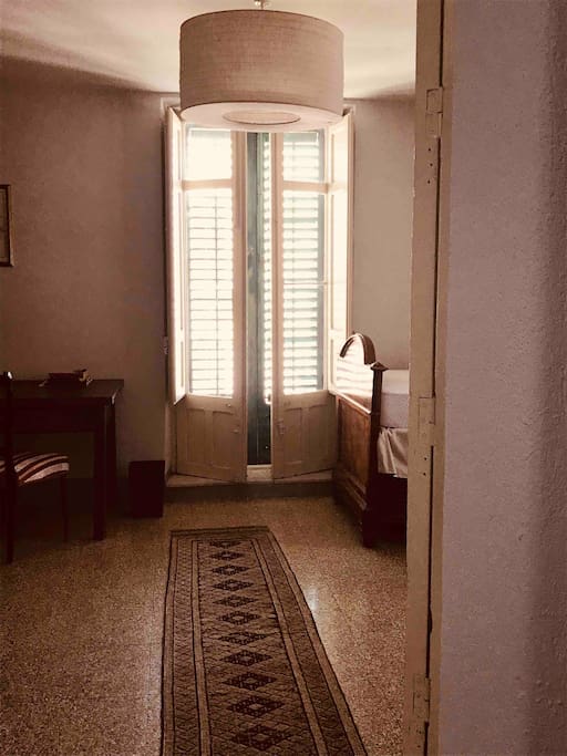 Entry to the bedroom with double doors that open onto a wraparound balcony overlooking the main piazza