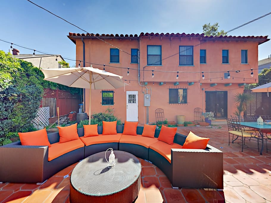 Expansive patio features an outdoor sectional, and a dining set with a large umbrella.