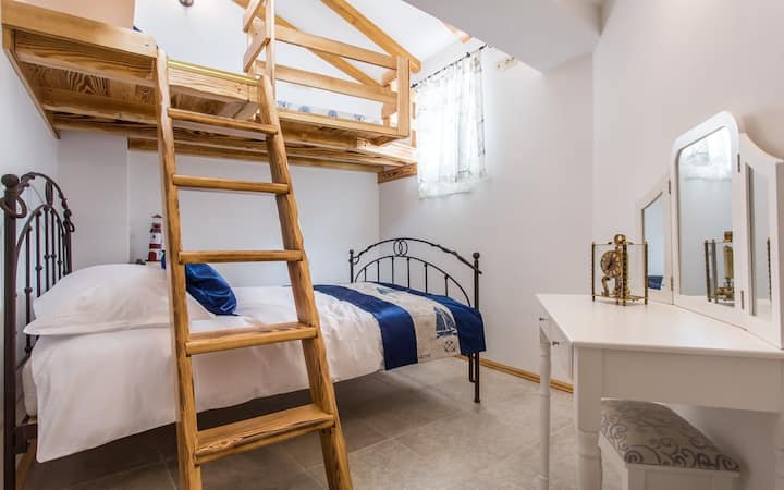 חדר שינה בקומת הקרקע של הבית עם מיטה זוגית וגלריה עם מיטה נוספת אחת  