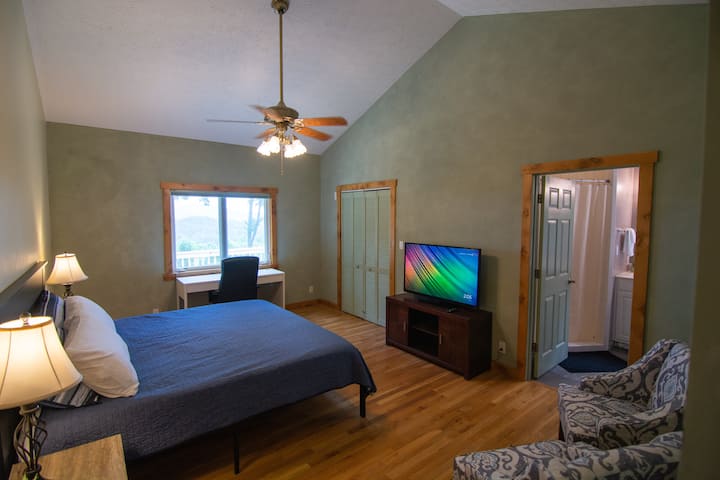 غرفة نوم رئيسية ؛ سرير كينج وتلفزيون ومنطقة جلوس. تحتوي المنافذ القريبة من كلا الطاولات الليلية على منفذين USB لشحن إلكترونياتك. المكتب في الخزانة. 