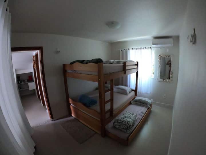 Habitación con aire acondicionado en el primer piso de la casa con una litera doble y cama auxiliar.