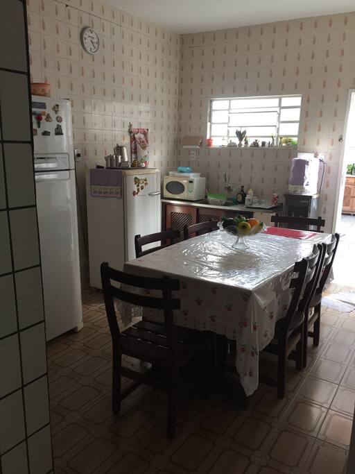 Cozinha, geladeira, microondas e mesa para refeições.