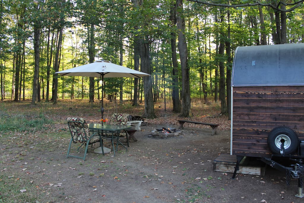 Accommodations complete with glass table, comfy chairs, umbrella, campfire, and firewood