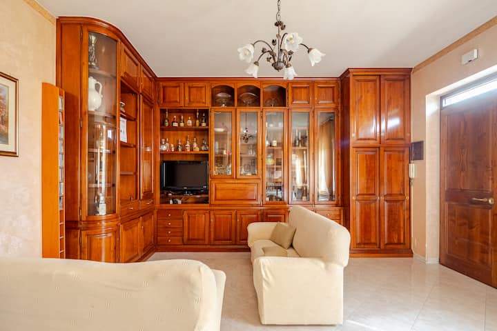 ห้องนั่งเล่นขนาดใหญ่สว่างไสวพร้อมโซฟาที่สะดวกสบาย พื้นที่รับประทานอาหาร และเฟอร์นิเจอร์ไม้สไตล์คลาสสิก สภาพแวดล้อมที่อบอุ่นและเหมาะสำหรับการพักผ่อนหรือแบ่งปันช่วงเวลากับเพื่อนร่วมงาน