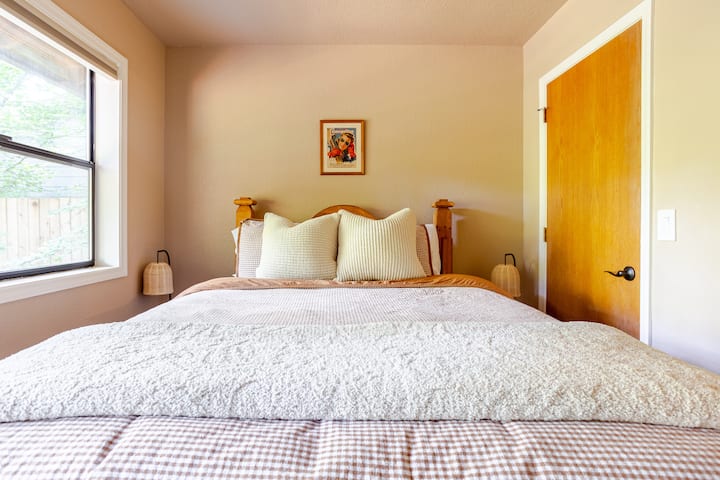 Uno de los dos dormitorios de abajo con una cama tamaño queen bien equipada y vista al jacuzzi y al patio trasero.