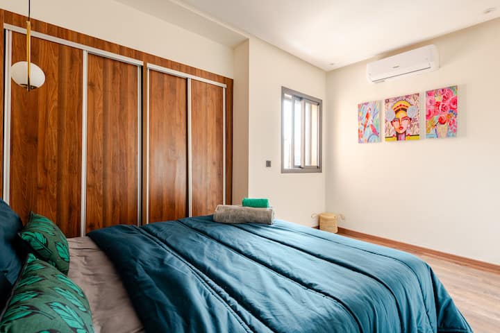 Un rifugio vivace e artistico pensato per il riposo. Questa camera da letto è dotata di una soffice testiera in velluto posizionata davanti a un murale colorato. Con lenzuola, asciugamani e un ampio armadio a muro, offre la perfetta combinazione di stile e comfort. Tutto chiaro e tranquillo!
