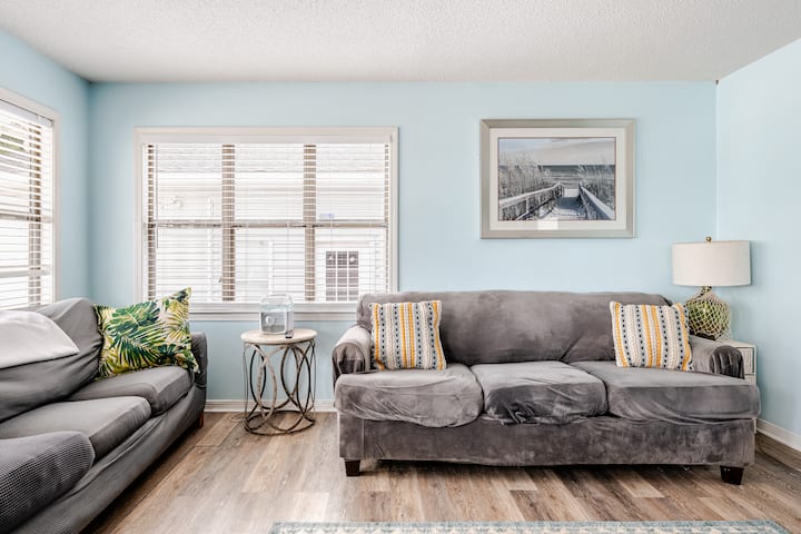 Ljust och inbjudande vardagsrum med bekväma sittplatser, stora fönster och en monterad TV perfekt för avkoppling efter en dag på vattnet eller utforska Orange Beach.