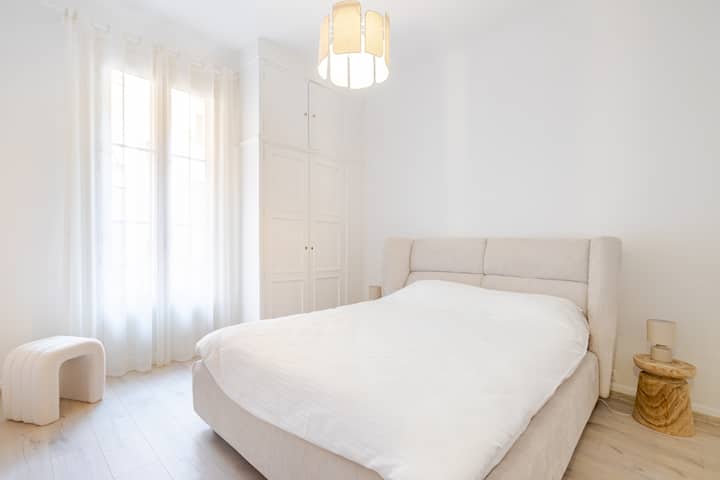 Los colores suaves y neutros crean un ambiente relajante, complementado con una acogedora cama tamaño queen y sábanas limpias. La ventana da acceso a un amplio balcón donde puedes disfrutar de un delicioso café por la mañana, preparándote para explorar la ciudad de Mónaco.