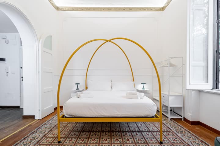 לגלות חדר שינה ייחודי עם מיטת פוסטר צהובה, תקרת פרסקו ורצפת פסיפס. מרוהטת בטוב טעם, היא מציעה פינת קריאה נעימה וחלונות גדולים לאור טבעי. מושלם לשהייה רגועה.