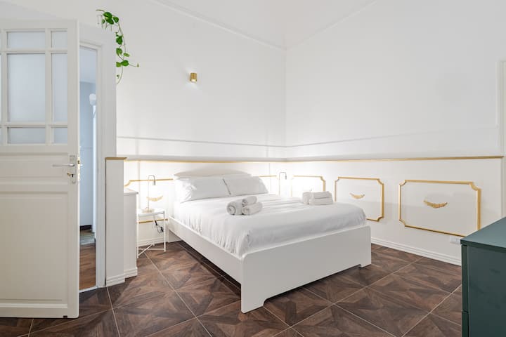 חדר מעודן עם פרטים מוזהבים וריהוט מסוגנן. מיטת קווין סייז נוחה, ארון גדול ואור טבעי. אווירה מוארת ומזמינה, אידיאלית לשהייה רגועה. מושלם למי שמחפש סגנון ונוחות.