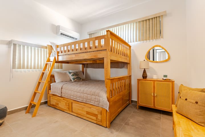 Family-friendly bedroom with sturdy wooden bunk beds, soft bedding, and warm natural light. Ideal for kids or groups seeking comfort and charm in a shared space.