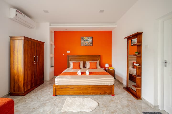 Citrus Bliss Suite- featuring a plush king-size bed, elegant wooden furnishings, and vibrant earthy tones. This spacious room is fully air-conditioned and comes with an attached bathroom and private balcony.