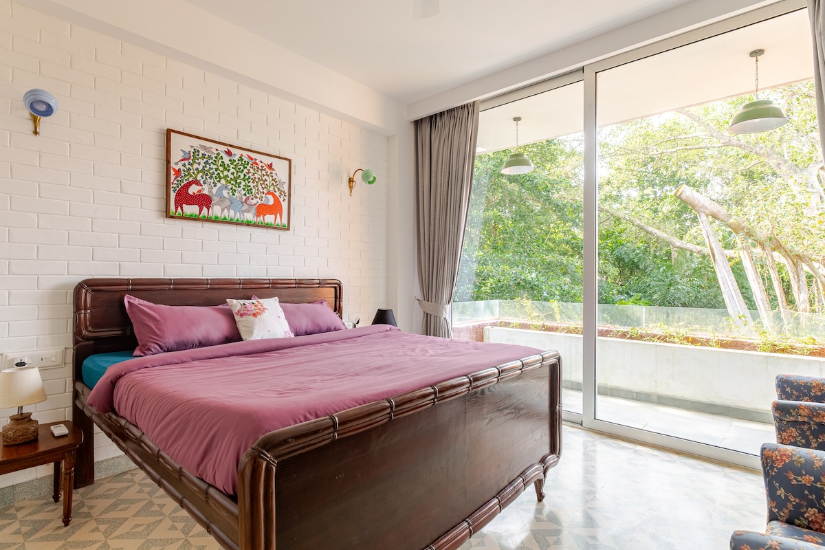 מיטת וינטג' משוחזרת עם מזרן קינג סייז. מרפסת המשקיפה אל תוך יער משמאל ועץ באניאן בחזית