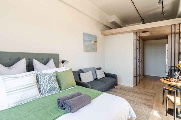"Desde la comodidad de la cama tamaño queen, disfruta de una vista hacia la cocina y una encantadora zona de loft de arriba, accesible por una elegante escalera, agregando un toque único a este acogedor estudio.
