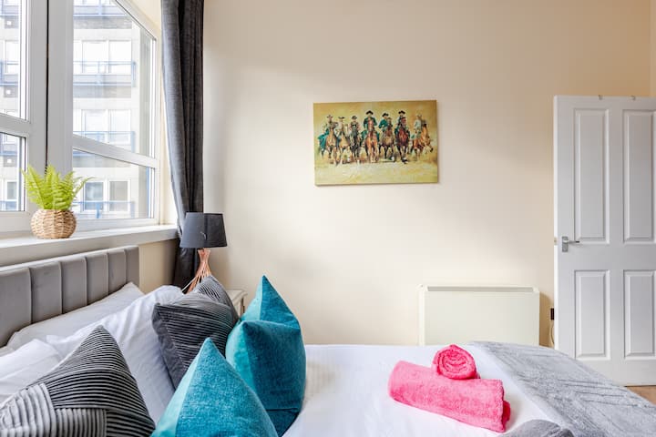 Un elegante dormitorio con una gran ventana que deja entrar abundante luz natural. Amplio espacio de almacenamiento, un televisor inteligente y una decoración contemporánea para una sensación cálida y acogedora. Cargadores USB junto a la cama