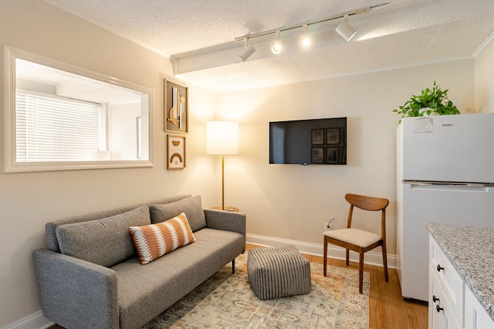 Sala de estar con un cómodo sofá con capacidad para tres personas  Además, el nuevo televisor de alta definición Roku de 43pulgadas con aplicaciones de streaming y un montón de canales gratuitos para tu visualización. La lámpara de pie proporciona mucha luz para leer. 