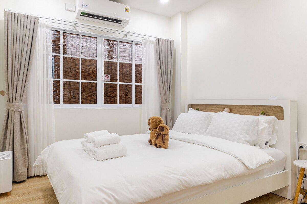 Un dormitorio acogedor con una cama tamaño queen, aire acondicionado para mayor comodidad, un espejo elegante, un soplador para mayor calidez, perchas de pared para un fácil almacenamiento y un ventilador para una brisa refrescante.
