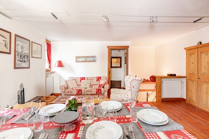 Sala de estar con sofá cama, TV,  sillón y mesa de comedor.
