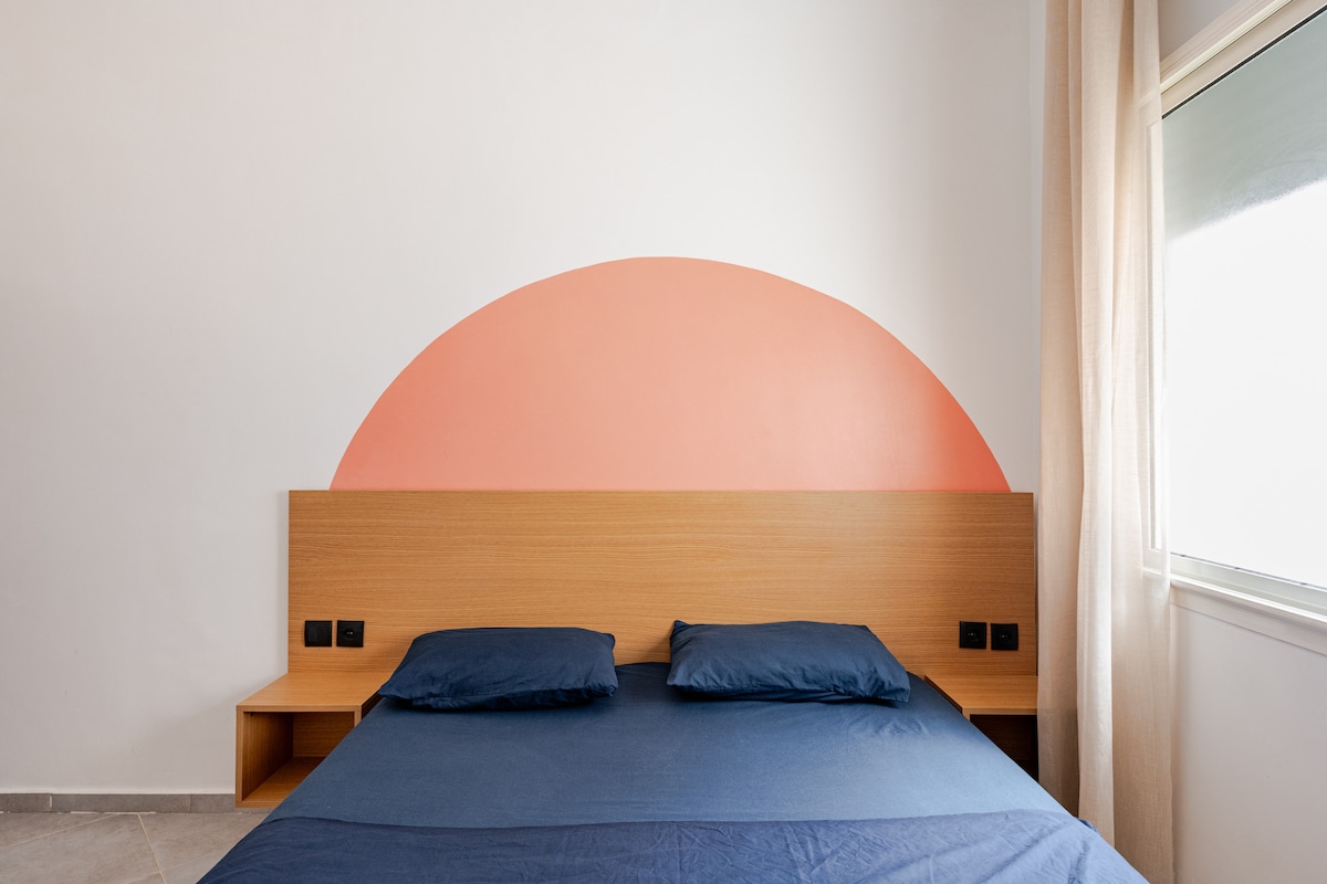 moderna i svijetla spavaća soba s terakota zidom i lukom. Udoban bračni krevet s plahtama, funkcionalno uzglavlje s pristupačnim električnim utičnicama i veliki prozor koji nudi prekrasno prirodno svjetlo. 