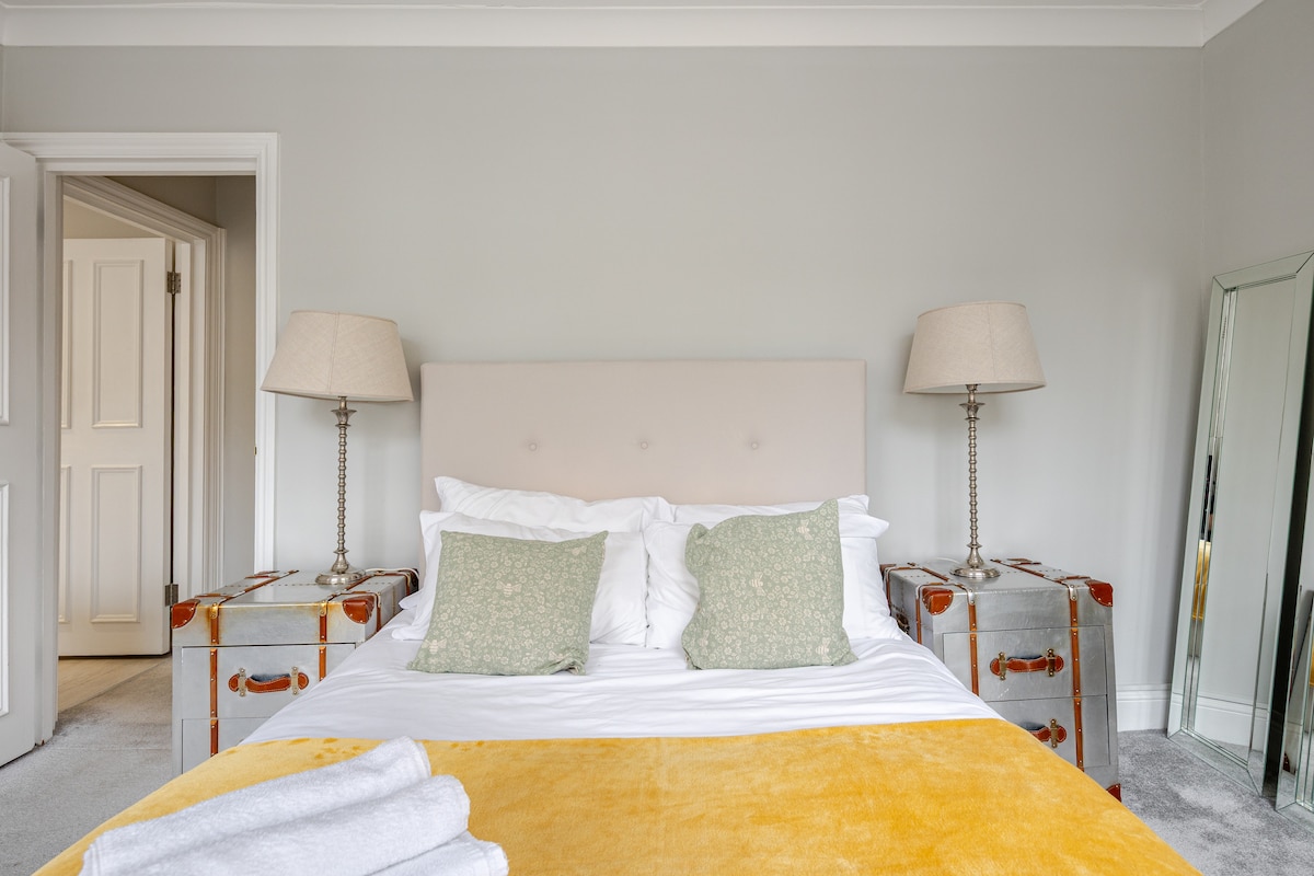 Stijlvolle en gezellige slaapkamer met een tweepersoonsbed, schoon beddengoed en een elegante inrichting. Zachte verlichting en neutrale tinten creëren een rustige sfeer, perfect om tot rust te komen, met nachtkastjes en lampen voor extra comfort.