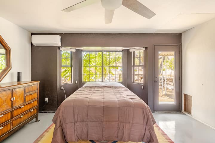 
Dormitorio principal con altavoces Bluetooth sobre la cama. Puerta trasera a la bañera de hidromasaje privada llena de agua filtrada por ósmosis inversa. 