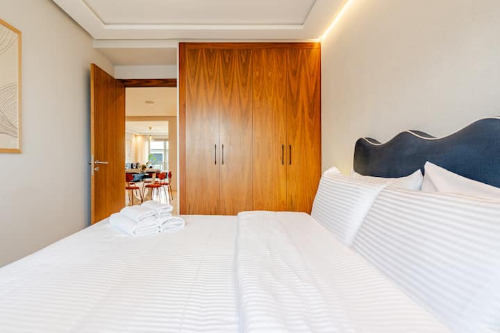 Ugodna druga spavaća soba s udobnim bračnim krevetom, svježom hotelskom posteljinom i velikim drvenim ormarom s dovoljno prostora za pohranu. Nježno osvjetljenje iznad uzglavlja, izravan pristup dnevnom boravku, savršeno za prijatelje, djecu ili kolege.