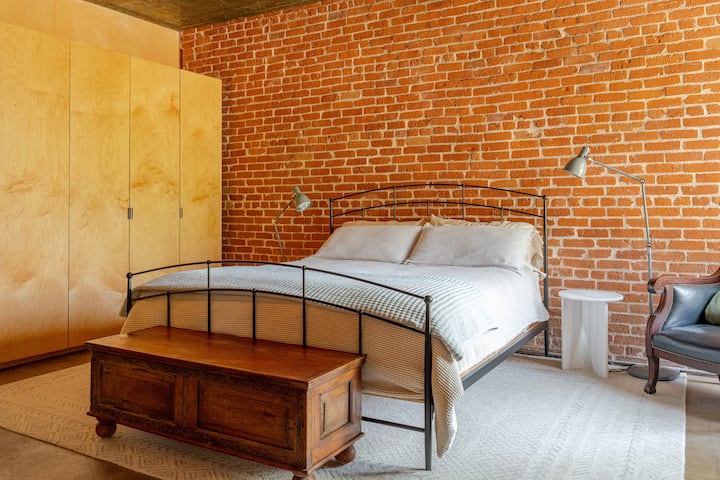 Cama tamaño king con pared lateral de ladrillo de arcilla roja