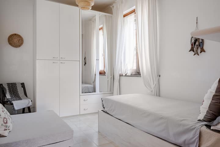 Este quarto tem duas camas, um guarda-roupa grande com uma cômoda integrada e prateleiras com tomadas elétricas. Mosquiteiro