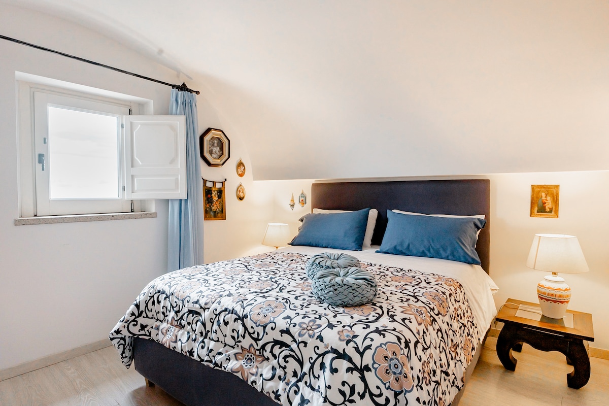 Spálňa na druhom poschodí. Izba má krásny výhľad na more na vyhliadkovú vežu „Torre del Capo di Conca“, ktorá sa nachádza na sugestívnom ostrohu ponorenom do hustej stredomorskej vegetácie.