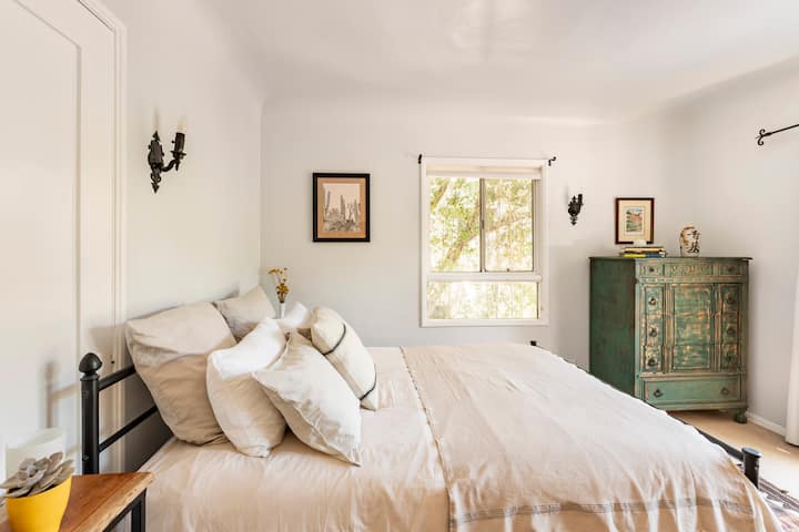 Cama orgánica tamaño queen con vistas a las puertas francesas de la ladera.