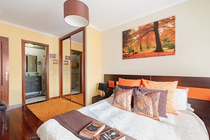 החדר הראשי מעוצב בגווני כתום וחום חמים, ומציע אווירה נעימה עם מיטה רכה של 1.50 מ', ארון מובנה מרווח עם דלתות מראה וטלוויזיה עם גישה לנטפליקס לרגעי המנוחה שלכם.