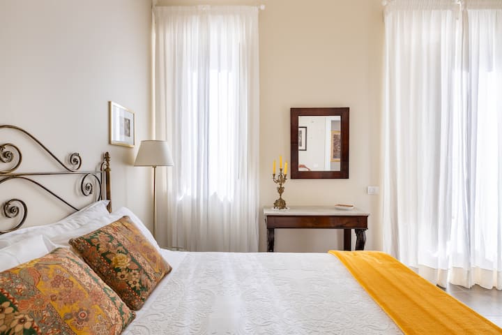 Bedroom on the floor, furnished with original antique furniture and large liberty chandelier. Air conditioning, balcony and window. King size bed, hypoallergenic mattress and double pillows. Original cement flooring. 