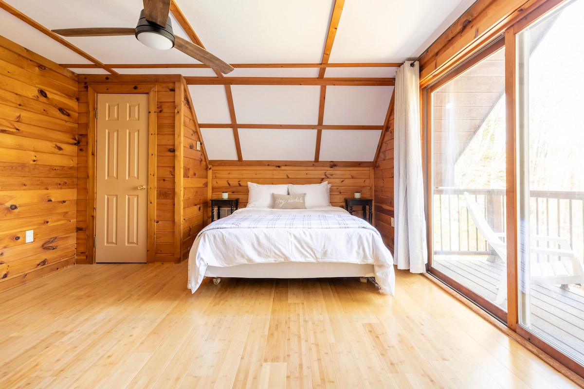 Upstairs primary suite (bedroom 2) with queen bed and twin bed, sitting area with vintage couch and chair, dresser and closet. Private balcony with 2 Adirondack chairs, perfect for morning coffee. Black out curtains.
