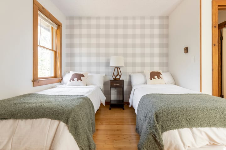 Main floor bedroom 3 with two twin beds, dresser, vintage writing desk and chair, and full length mirrored closet doors 