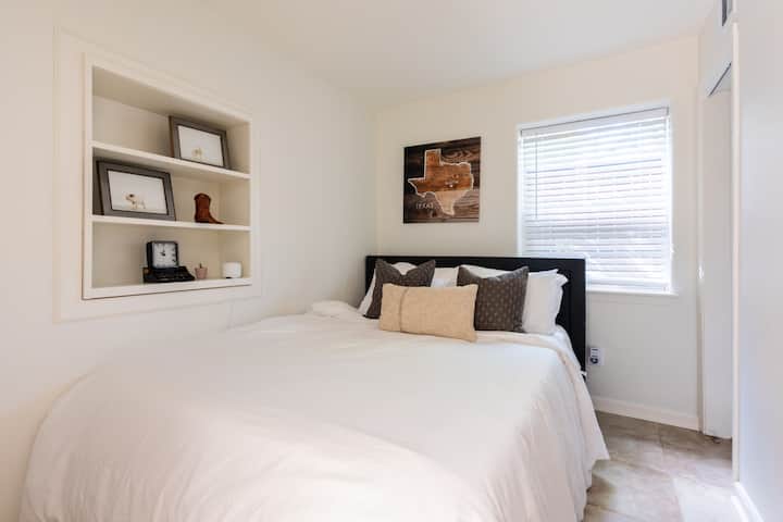 Chumba cha kulala #4 (ghorofa ya chini) kina kitanda cha Queen kilicho na mashuka meupe na mguso wa Austin wenye mandhari ya magharibi.