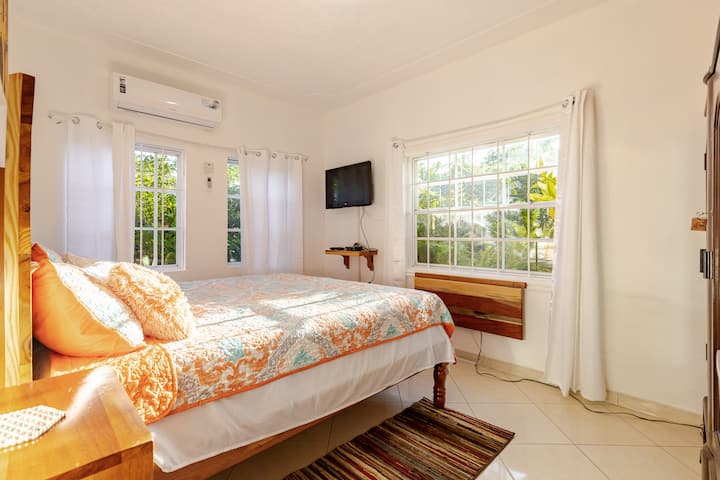 Amplio dormitorio tamaño king con aire acondicionado, luz natural y vistas al jardín, diseñado para noches de descanso y estancias más largas.