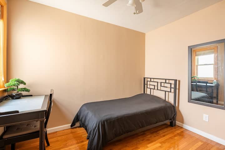 غرفة نوم متوسطة بسرير مزدوج الحجم. مروحة سقف. ستائر سوداء. مكتب وكرسي. كاليفورنيا مبنية في الخزانات. 