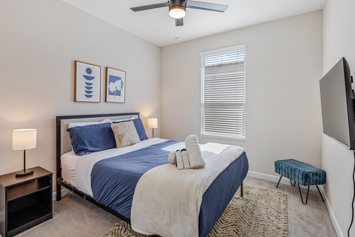 Удобна гостинска спална соба со удобен брачен кревет, стилски декор и монтиран телевизор за забава.