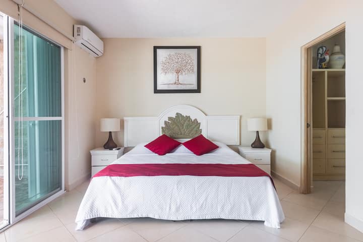 Dormitorio junto a la piscina con cama King, baño privado y aire acondicionado.