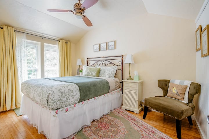 Ángulo más amplio del dormitorio principal. Una cómoda cama tamaño queen con volante para el polvo. Una mesita de noche y una lámpara a cada lado para esos teléfonos inteligentes y bebidas. Silla lateral para relajarse y ponerse zapatos. 