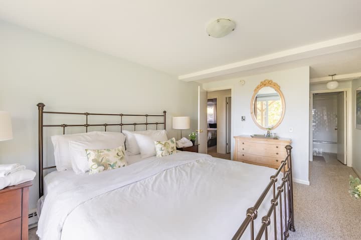 Main bedroom located on lower level features en suite bathroom and sliders to patio and seasonal views.