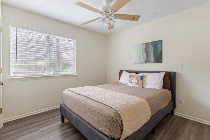 Relax in a peaceful bedroom with soft bedding and bright windows. This cozy setup gives guests a comfortable place to unwind after exploring New Braunfels.