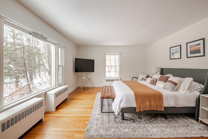 Large Primary King bedroom suite complete with a onsite bathroom, working desk, dresser, sitting area, large 65' TV, and a king Purple Mattress, organic cotton sheets, orthopedic pillows + feather pillows, AC, and blackout blinds