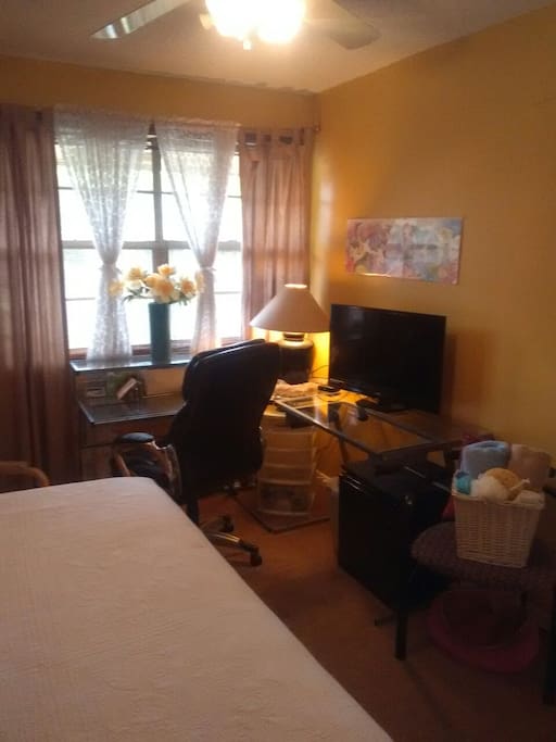 An "L" shaped glass desk has a TV, lamp and an executive chair for your comfort. A recliner in the other corner invites you to relax and enjoy a cold drink from your mini refrigerator under the desk.